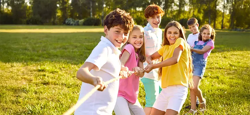 Des enfants tirent fort sur une corde, concentrés et souriants.