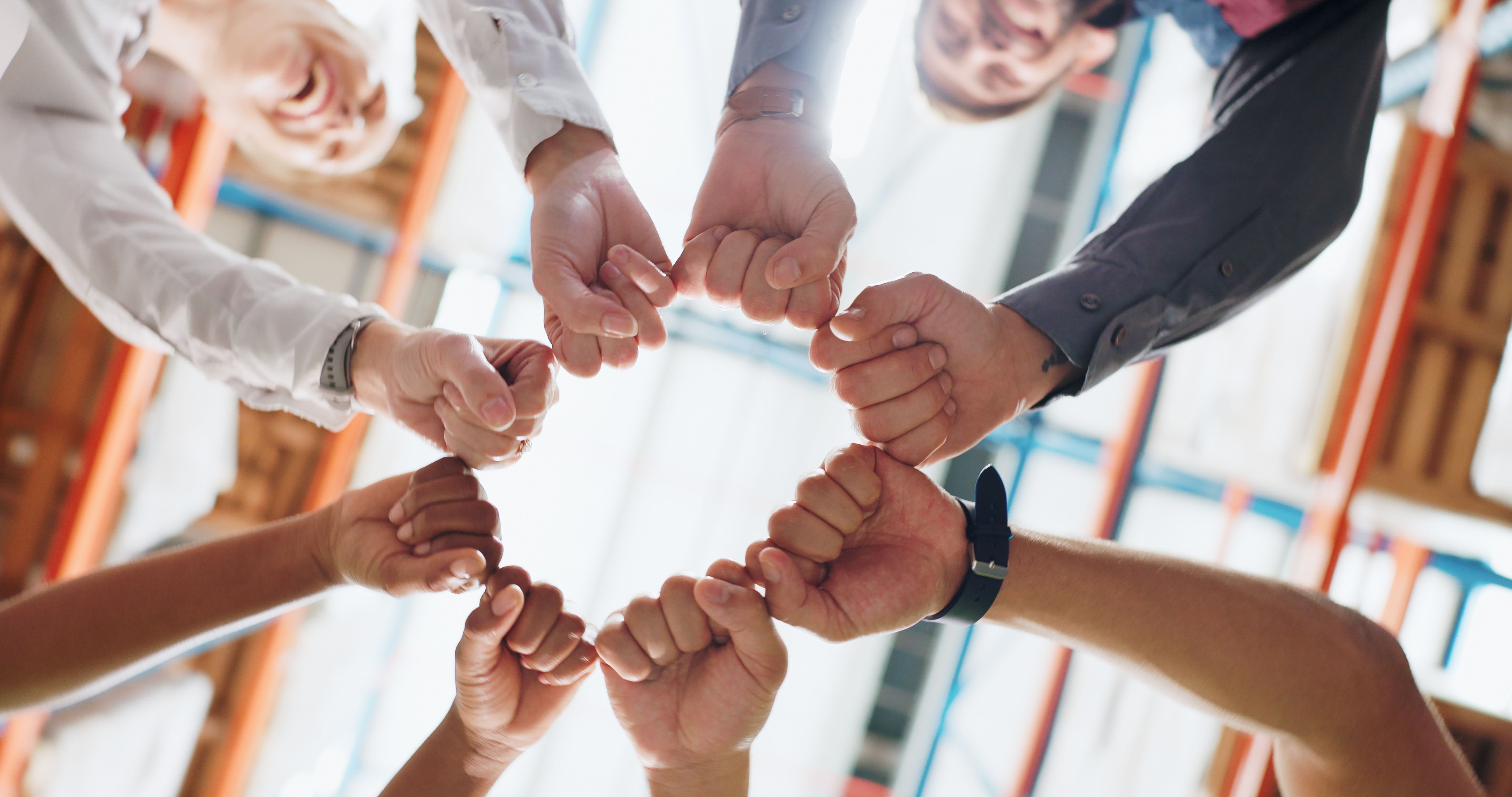Un groupe de collègues forme un cercle avec leurs mains exprimant un sentiment d’appartenance